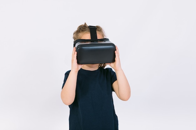 Little girl wearing virtual reality glasses with hands hold goggles on white background