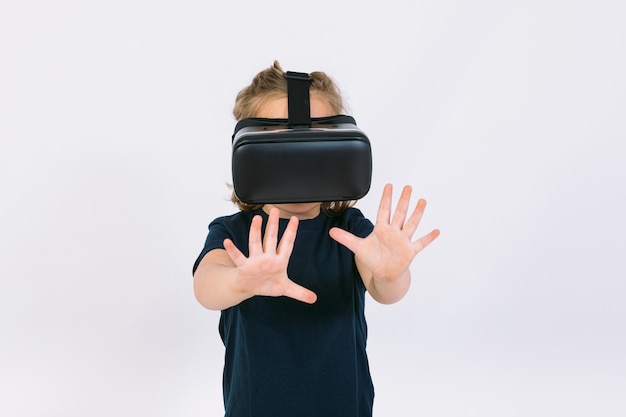 Little girl wearing virtual reality glasses with hands trying to touch something virtually