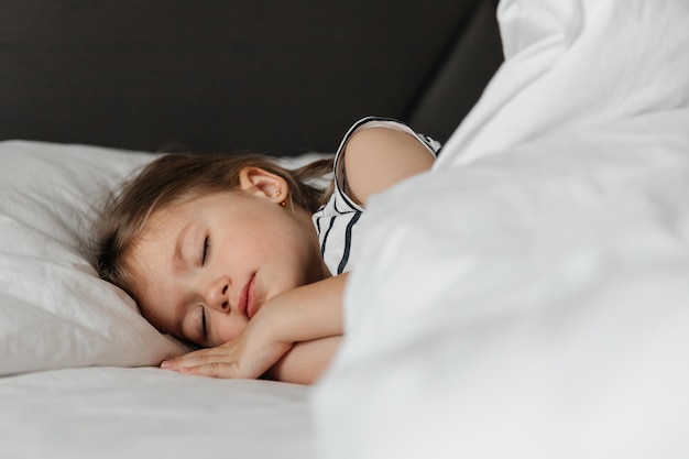 The little girl went to bed for a nap in her parents\' bed\
portrait of a girl falling asleep in bed during the day