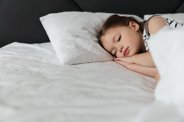 The little girl went to bed for a nap in her parents\' bed\
portrait of a girl falling asleep in bed during the day