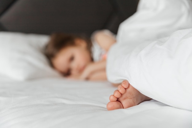 The little girl went to bed for a nap in her parents' bed Portrait of a girl falling asleep or waking up in bed during the day