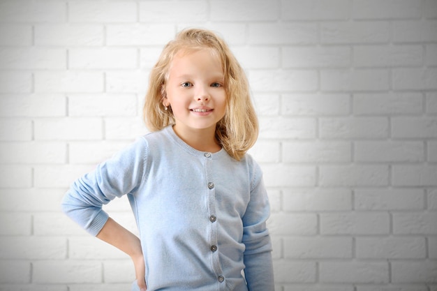 Маленькая девочка на фоне стены из белого кирпича