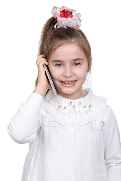 Little girl in a white dress smiling and talking on the smartphone isolated on white background