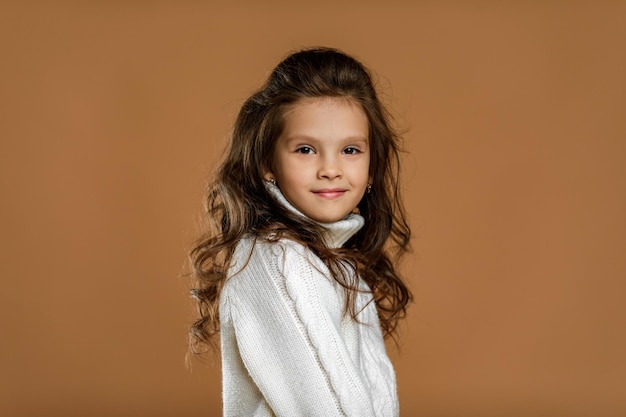 Little girl in white sweater looking to camera