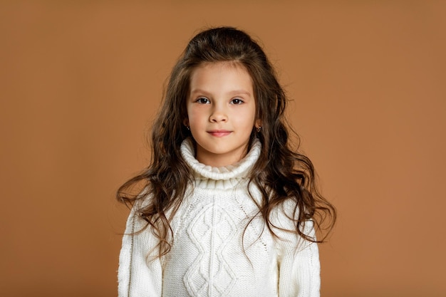 Little girl in white sweater looking to camera