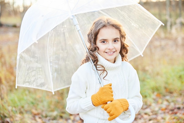 Little girl in a white sweater with a white umbrella in nature. High quality photo