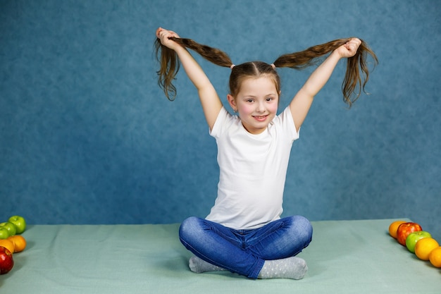 Photo little girl in a white t-shirt and jeans fooling around with her hair