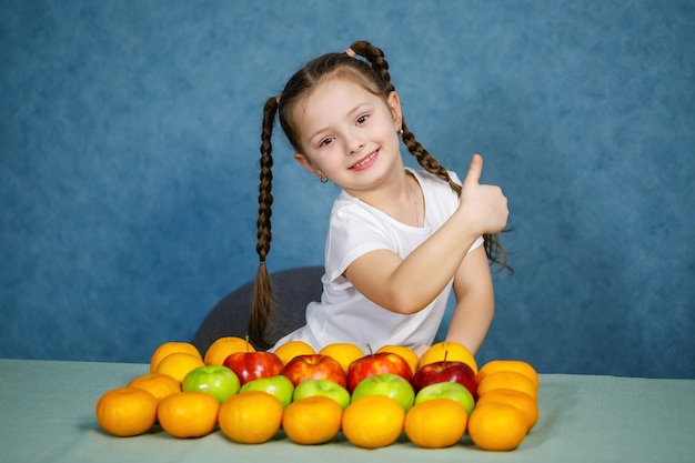 흰색 티셔츠를 입은 어린 소녀는 과일을 좋아합니다.