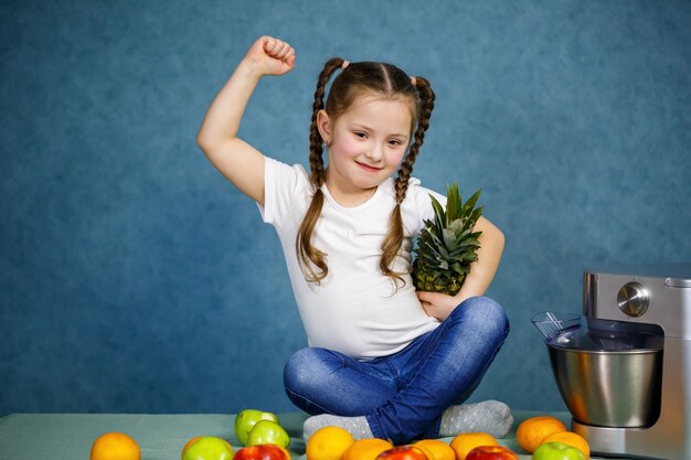 Photo little girl in a white t-shirt loves fruits. she holds a pineapple in her hands