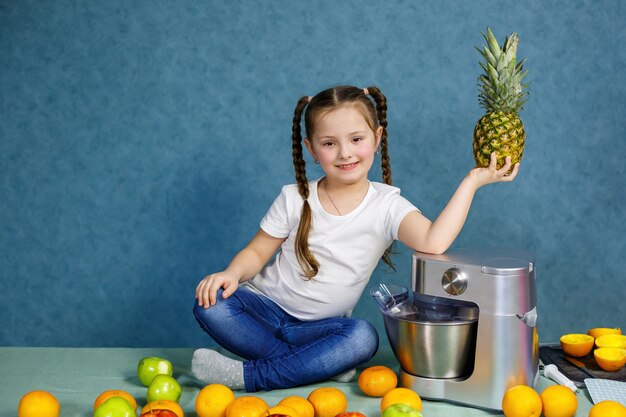 Маленькая девочка в белой футболке любит фрукты. В руках она держит ананас