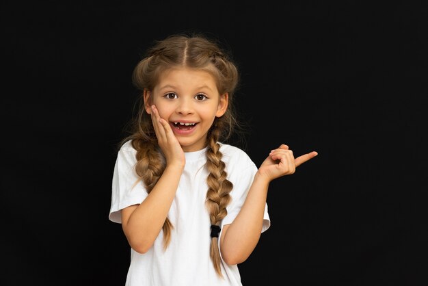 白いTシャツを着た小さな女の子は驚きを示しています。