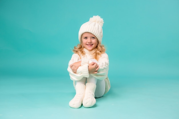 Bambina in inverno bianco cappello lavorato a maglia e maglione su blu