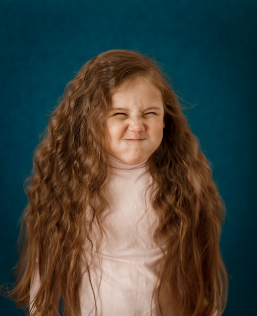 Little girl winces on a blue background