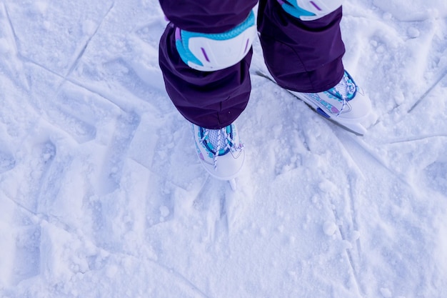 Little girl in winter clothes with protections skating on ice rink learning training first lesson on ice winter activities