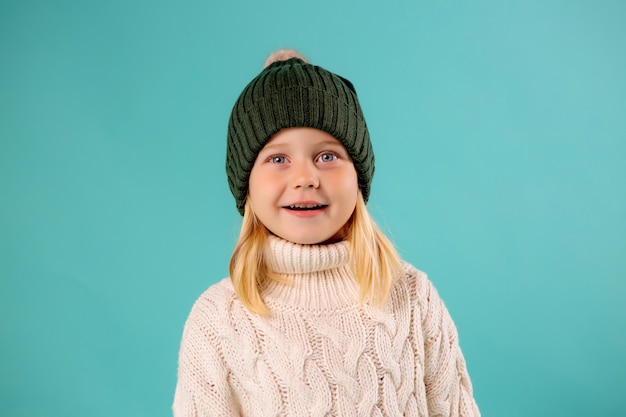 Bambina in cappello e maglione di inverno sull'azzurro