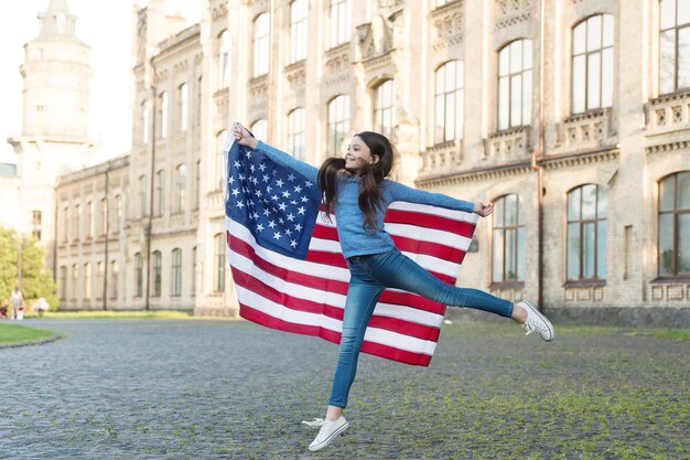 Little girl with american flag outdoors architecture background education abroad concept