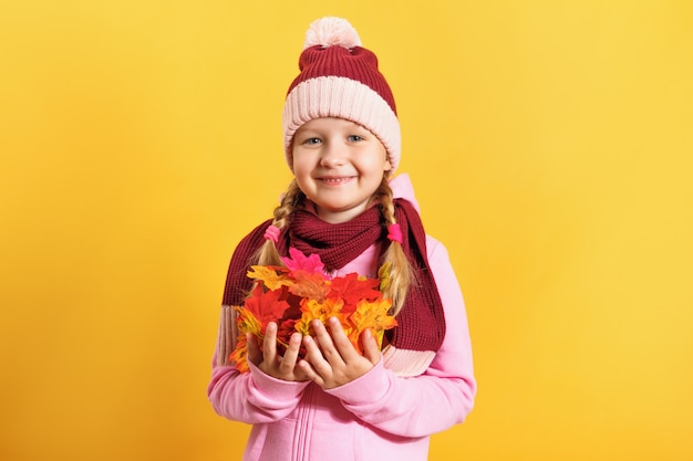 Little girl with an armful of autumn maple leaves.