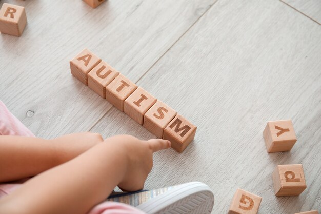 Little girl with autistic disorder playing with cubes on floor