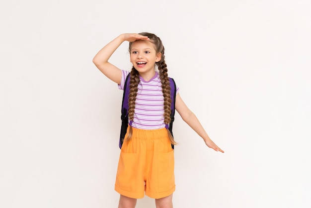 A little girl with a backpack on her back peering into the distance on a white isolated background Courses for summer education of children