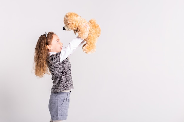 little girl with bear standing on white