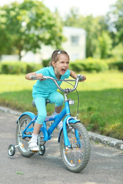 Little girl with bicycle outdoors in summer