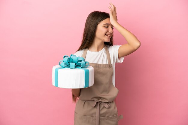 Little girl with a big cake over isolated pink background has realized something and intending the solution