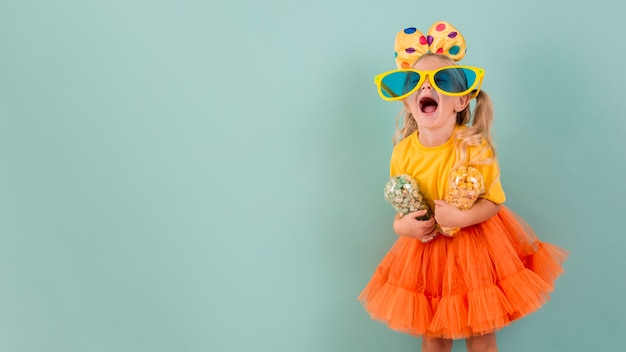 Bambina con grandi occhiali da sole tenendo la caramella