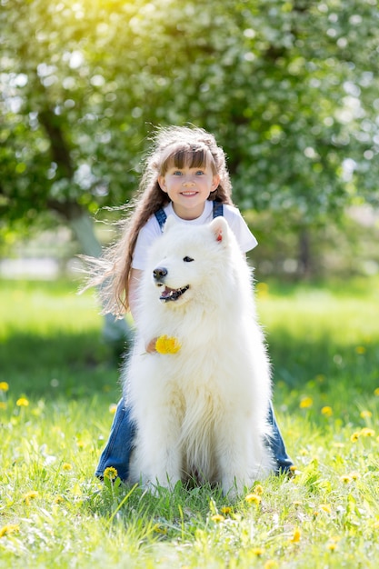 Little girl with a big white dog in the park.