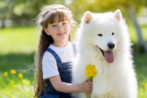 Bambina con un grande cane bianco nel parco.