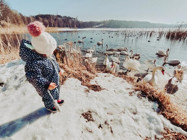 Photo little girl with birds in winter against sky