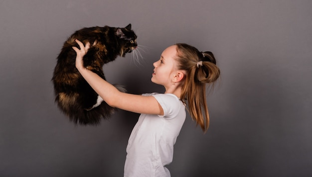 Little girl with black kitty, isolated on grey back