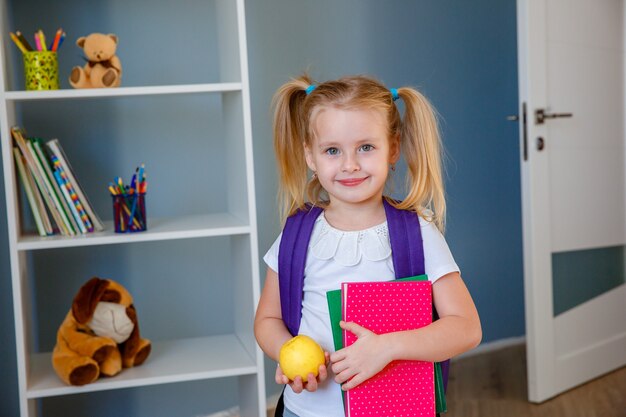 A little girl with a book and an Apple in her hands