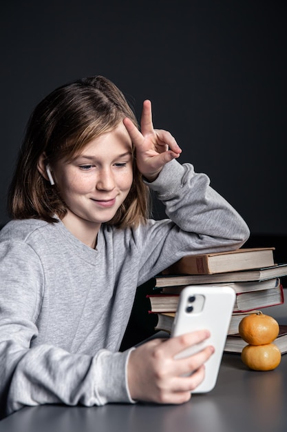 Little girl with books and a phone in her hands