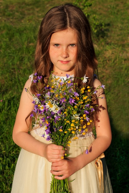 野生の花の花束を持つ少女