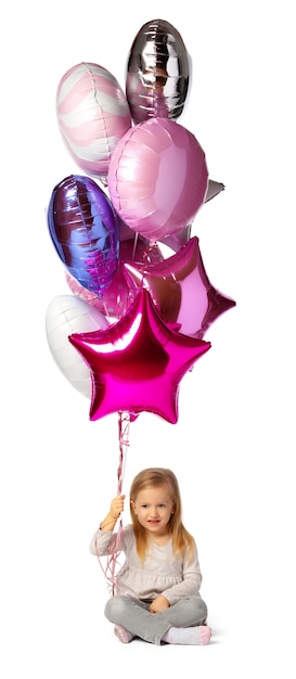 Little girl with a bunch of balloons sitting isolated on white background