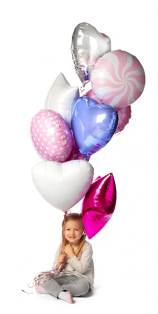 Little girl with a bunch of balloons sitting isolated