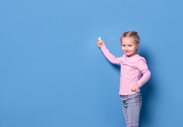 Little girl with chalk on blue background