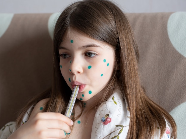 Foto una bambina con la varicella misura la sua temperatura