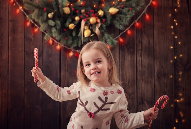 Bambina con le decorazioni di natale su fondo di legno scuro