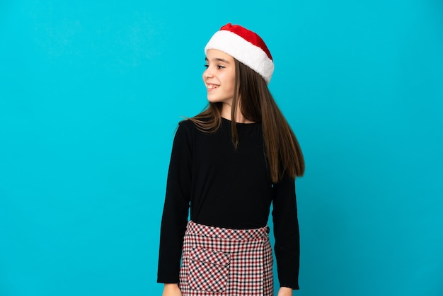 Little girl with Christmas hat isolated looking to the side and smiling