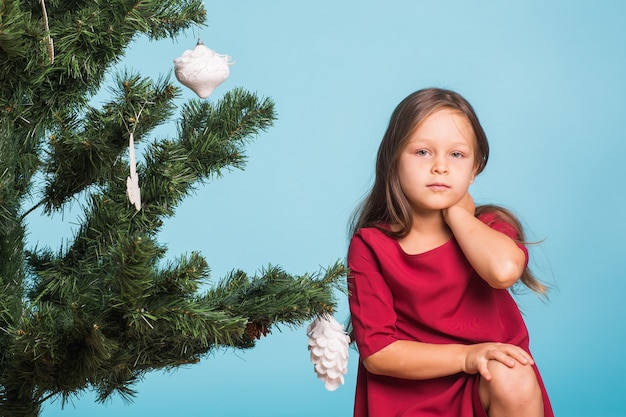 Little girl with christmas tree on blue background