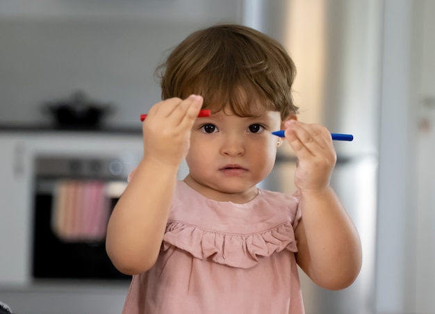 little girl with colored crayons while painting at home