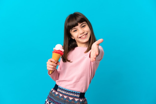 좋은 거래를 닫기 위해 악수하는 파란색 벽에 고립 된 코넷 아이스크림 어린 소녀