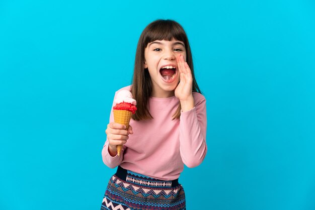 Photo little girl with a cornet ice cream isolated on blue wall shouting with mouth wide open