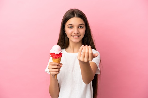 手で来るように誘う孤立したピンクの背景の上にコルネットアイスクリームを持つ少女。あなたが来て幸せ