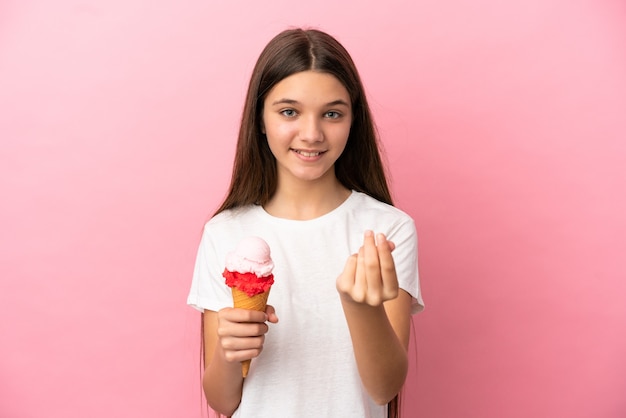 Little girl with a cornet ice cream over isolated pink background making money gesture