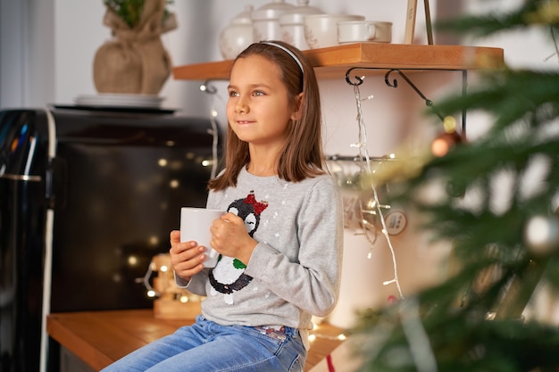 A little girl with a cup of hot tea at Christmas