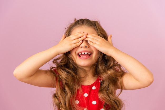 A little girl with curly hair covered her face with her hands.