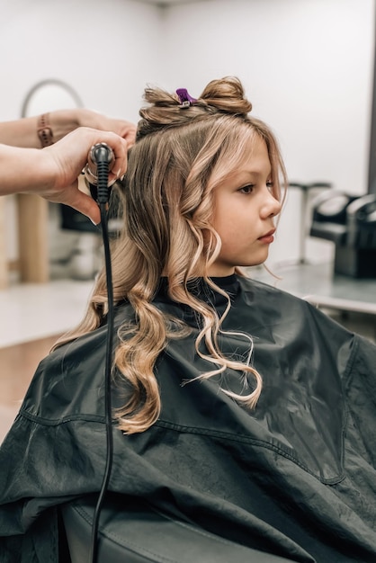 Little girl with curly hair Kid at the hairdresser