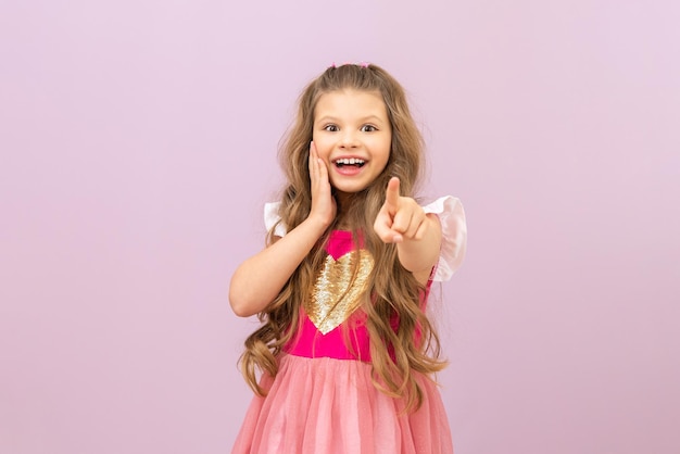 A little girl with curly hair points her finger forward Isolated background